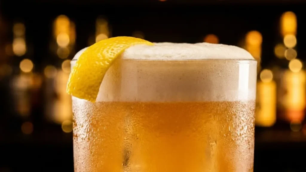 Amaretto Sour Recipe 12 Close-up Amaretto Sour with thick foam and lemon twist, glowing under warm bar lights. - Amaretto Sour Recipe