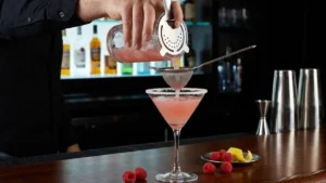 Raspberry Lemon Drop Cocktail Recipe – Bright, Boozy & Ready in Minutes 18 Raspberry lemon drop cocktail being strained into a sugar-rimmed martini glass