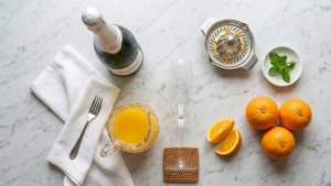 Classic Mimosa Recipe 14 Mimosa ingredients including champagne, fresh oranges, and orange juice on a kitchen counter