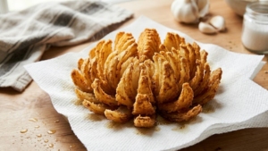 crispy blooming onion draining on paper towels after frying